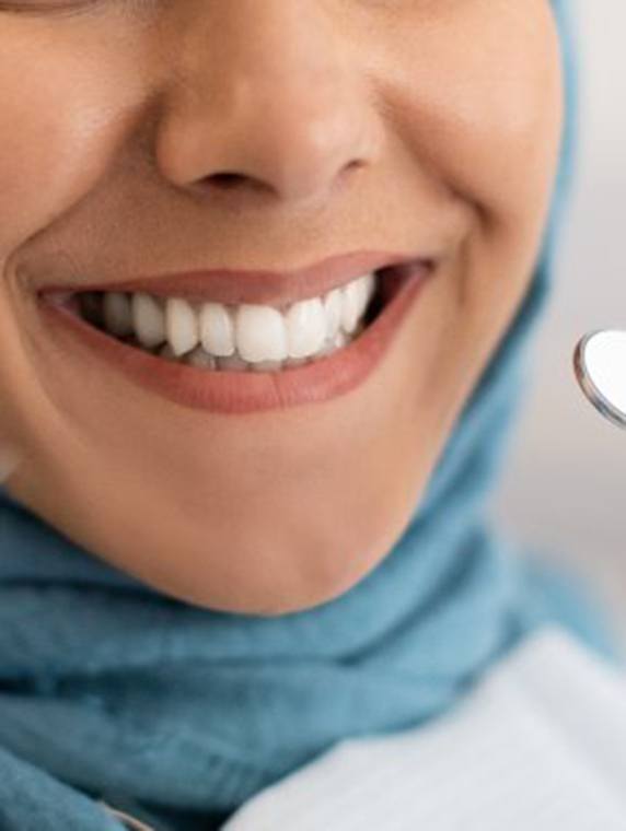 Patient smiling while dentist holds dental tools