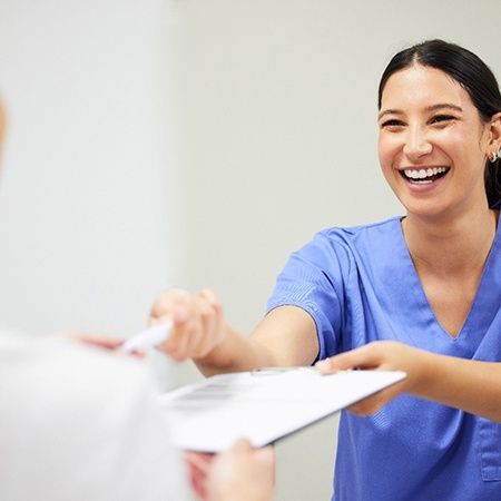 a dental office employee handing a patient forms
