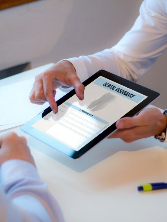 Two people at desk looking at dental insurance information on a tablet